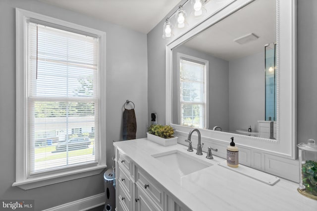 bathroom with vanity, toilet, and a healthy amount of sunlight