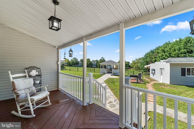 wooden deck with a gazebo, covered porch, and a lawn