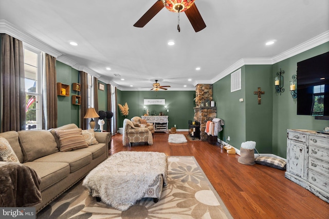 living room featuring ornamental molding, hardwood / wood-style floors, ceiling fan, and a fireplace