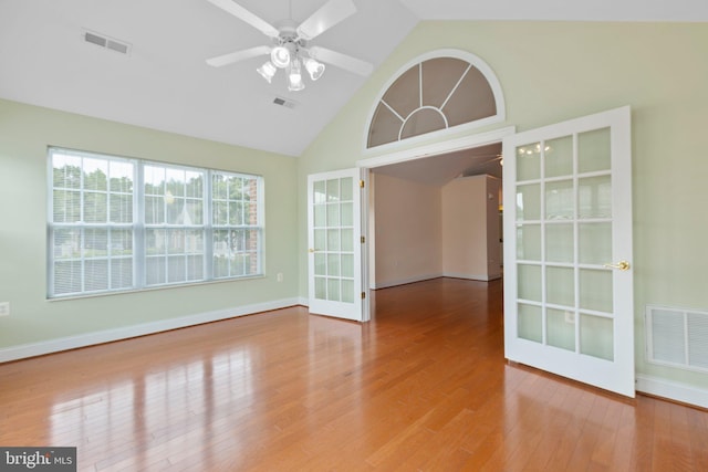 unfurnished room with hardwood / wood-style floors, french doors, high vaulted ceiling, and ceiling fan