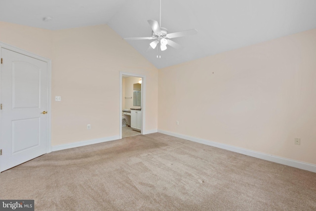 interior space with ceiling fan, light colored carpet, ensuite bathroom, and vaulted ceiling