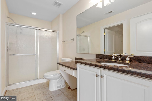 bathroom featuring tile patterned flooring, vanity, toilet, and a shower with door