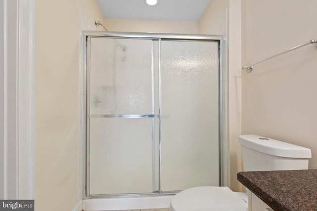 bathroom featuring vanity, toilet, and a shower with shower door