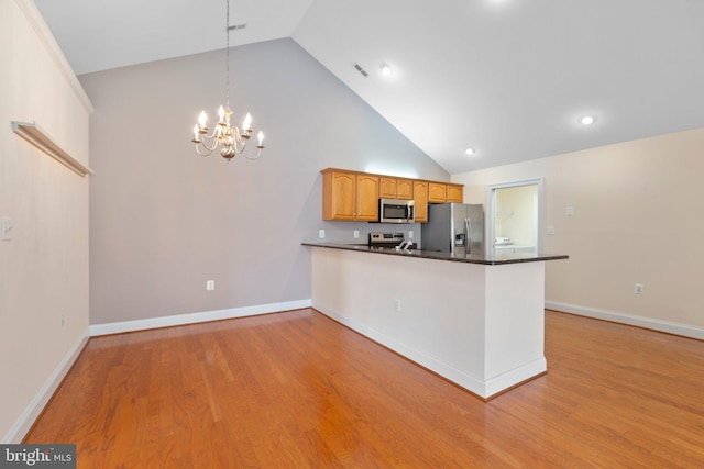 kitchen featuring kitchen peninsula, pendant lighting, stainless steel appliances, and light hardwood / wood-style floors