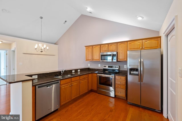 kitchen with sink, stainless steel appliances, dark hardwood / wood-style floors, kitchen peninsula, and decorative light fixtures