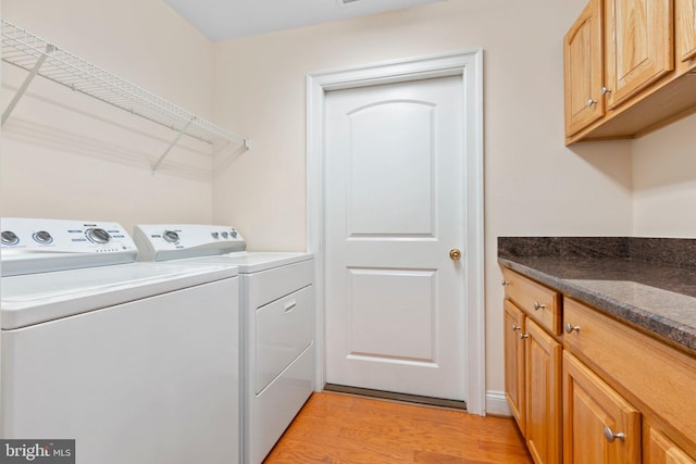 washroom with separate washer and dryer, light hardwood / wood-style flooring, and cabinets