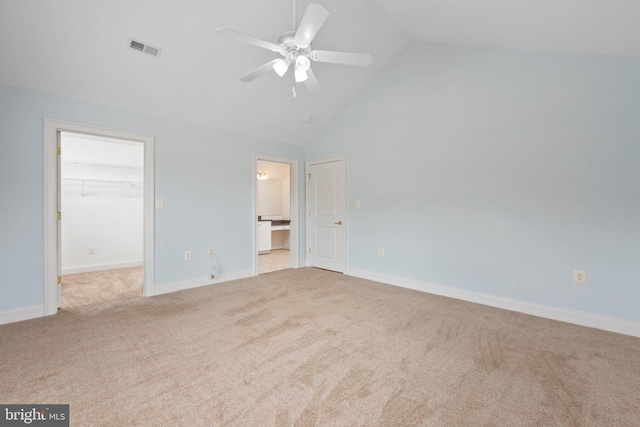 unfurnished bedroom featuring light carpet, a walk in closet, ceiling fan, a closet, and lofted ceiling