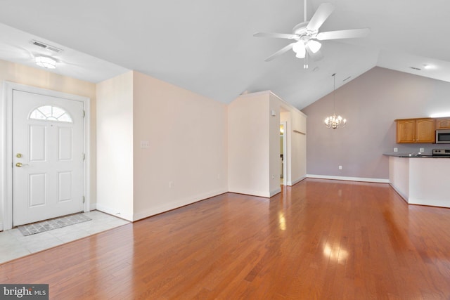 unfurnished living room featuring ceiling fan with notable chandelier, light hardwood / wood-style floors, and lofted ceiling