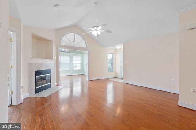 unfurnished living room featuring plenty of natural light, ceiling fan, a tile fireplace, and light hardwood / wood-style flooring