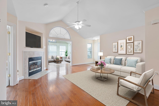 living room with ceiling fan, light hardwood / wood-style floors, a fireplace, and high vaulted ceiling