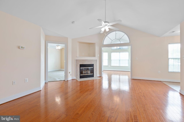 unfurnished living room with plenty of natural light, light hardwood / wood-style floors, lofted ceiling, and a tile fireplace