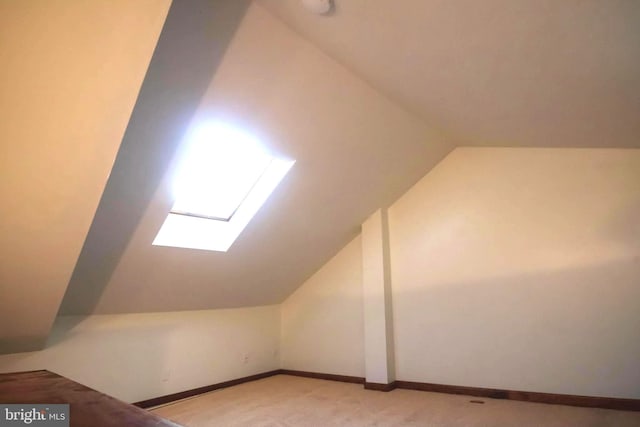 bonus room featuring lofted ceiling with skylight and light colored carpet