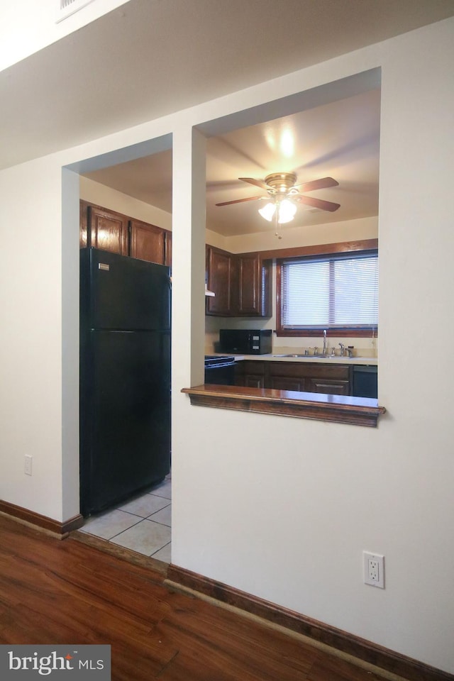 kitchen with ceiling fan, black refrigerator, sink, and light hardwood / wood-style flooring