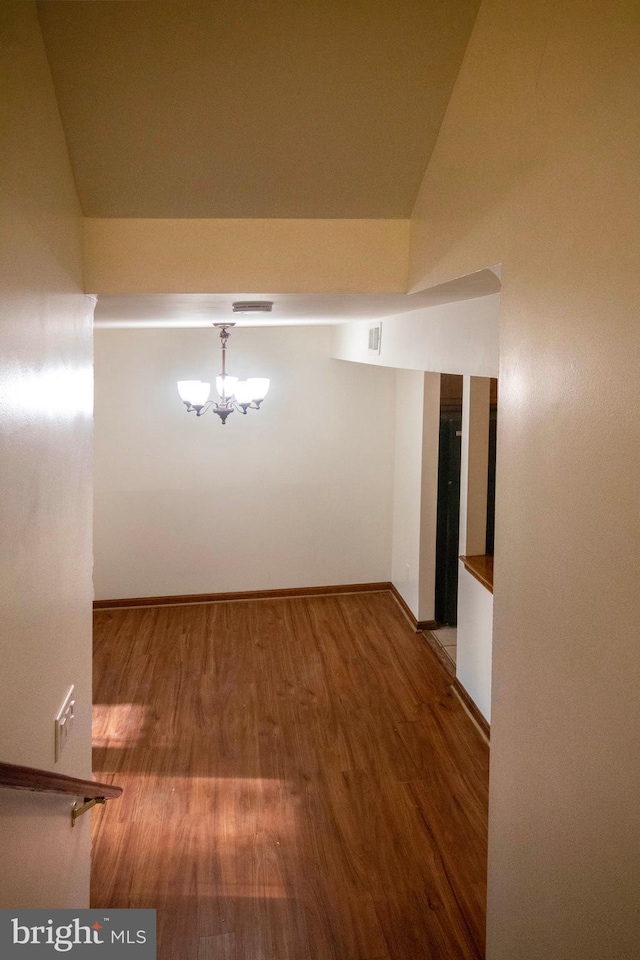 interior space featuring wood-type flooring, an inviting chandelier, and vaulted ceiling