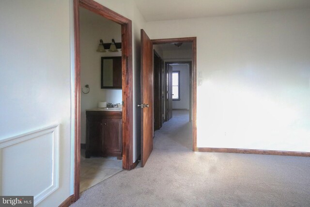 hallway with light carpet and sink