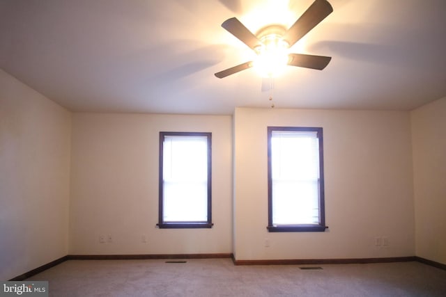 unfurnished room with a wealth of natural light, ceiling fan, and light carpet