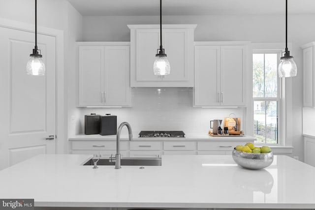 kitchen with white cabinetry, sink, a healthy amount of sunlight, and decorative light fixtures