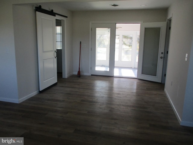 unfurnished room with a barn door and dark hardwood / wood-style floors