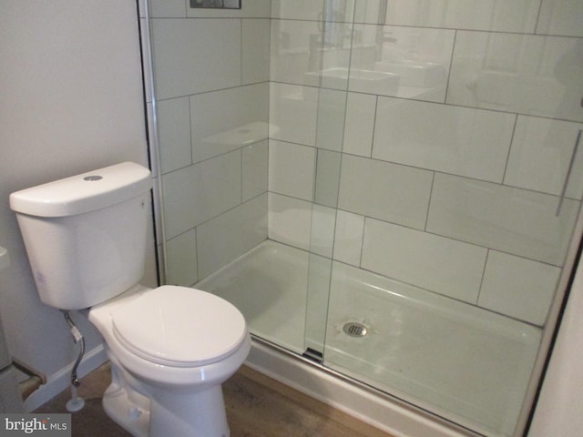 bathroom featuring toilet and a shower with shower door