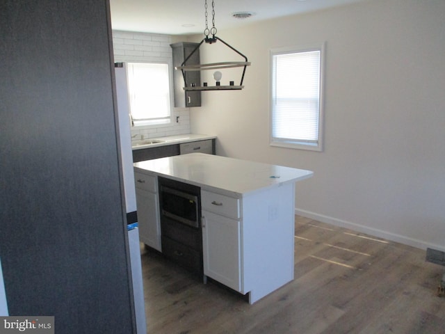 kitchen with decorative light fixtures, white cabinetry, plenty of natural light, and a kitchen island