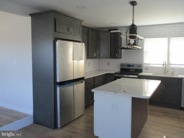 kitchen with backsplash, sink, appliances with stainless steel finishes, a kitchen island, and wood-type flooring