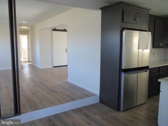 kitchen featuring stainless steel fridge, backsplash, a barn door, and hardwood / wood-style floors