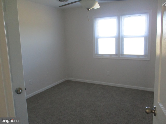 empty room featuring ceiling fan and dark carpet