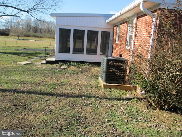 view of property exterior with a sunroom, central AC unit, and a yard