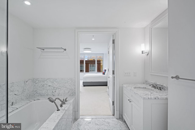 bathroom featuring a relaxing tiled tub and vanity