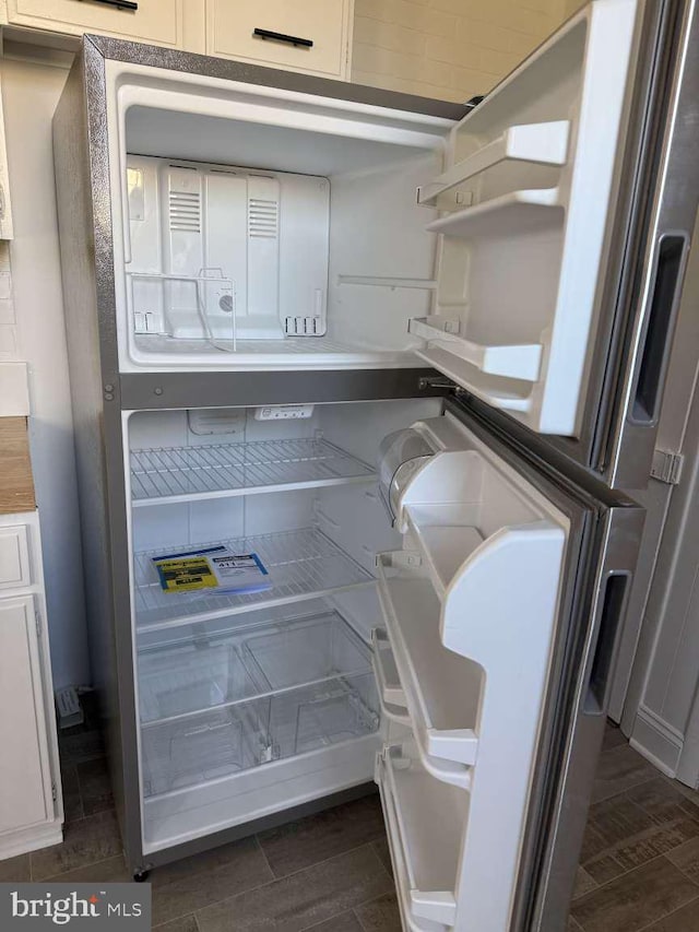 interior details with white cabinets, dark hardwood / wood-style floors, and fridge