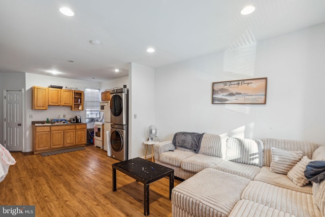 living room featuring sink, light wood-type flooring, and stacked washer and dryer