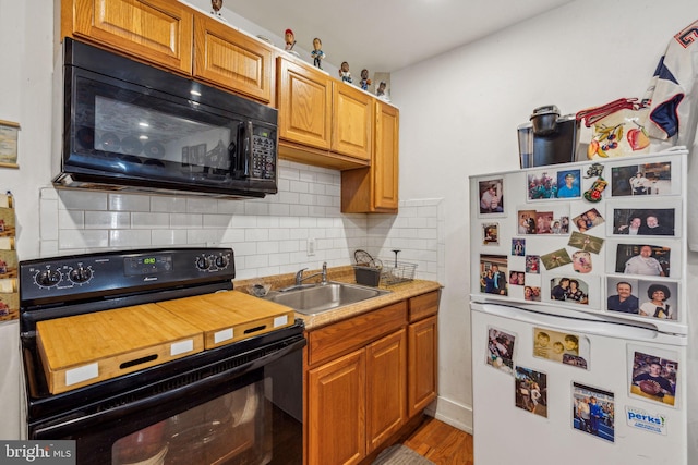 kitchen featuring black appliances, backsplash, sink, and light hardwood / wood-style flooring