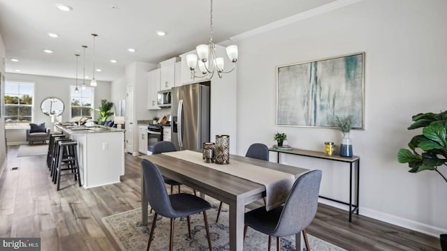 dining space featuring hardwood / wood-style floors, ornamental molding, a notable chandelier, and sink