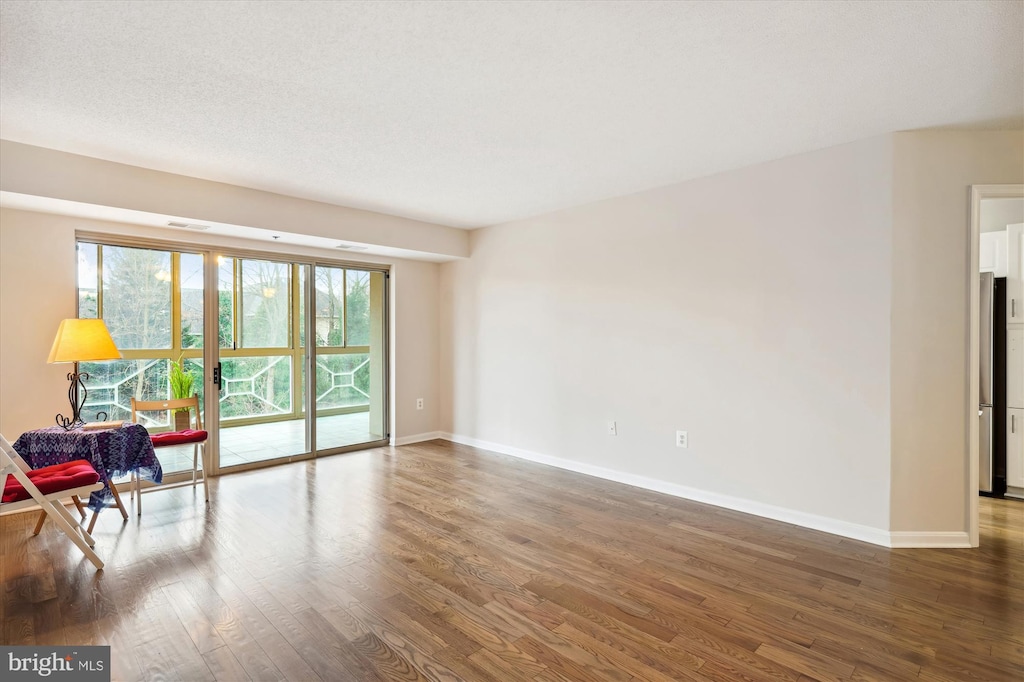 empty room featuring a textured ceiling and dark wood-type flooring