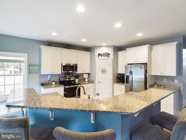 kitchen with a kitchen breakfast bar, white cabinetry, and appliances with stainless steel finishes