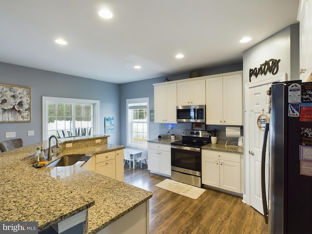 kitchen featuring appliances with stainless steel finishes, dark wood-type flooring, sink, white cabinetry, and an island with sink