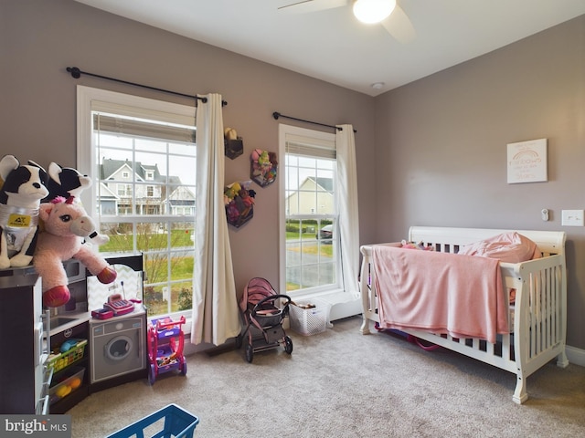 bedroom with a crib, carpet, and ceiling fan