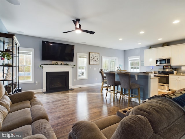 living room featuring ceiling fan, a healthy amount of sunlight, and light wood-type flooring