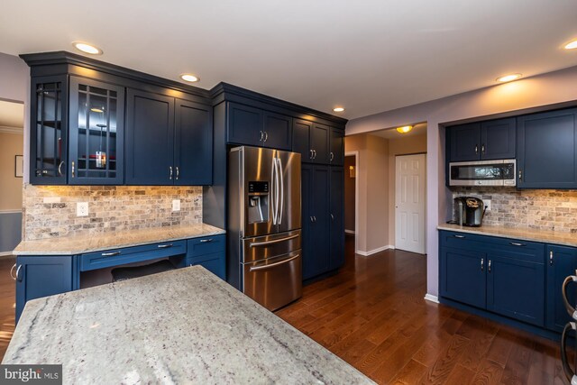 kitchen with dark hardwood / wood-style floors, light stone countertops, appliances with stainless steel finishes, and tasteful backsplash