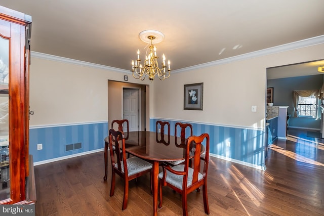 dining area featuring crown molding, dark hardwood / wood-style flooring, and a notable chandelier