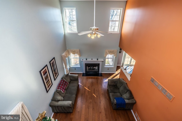 living room with ceiling fan, plenty of natural light, dark wood-type flooring, and a high ceiling