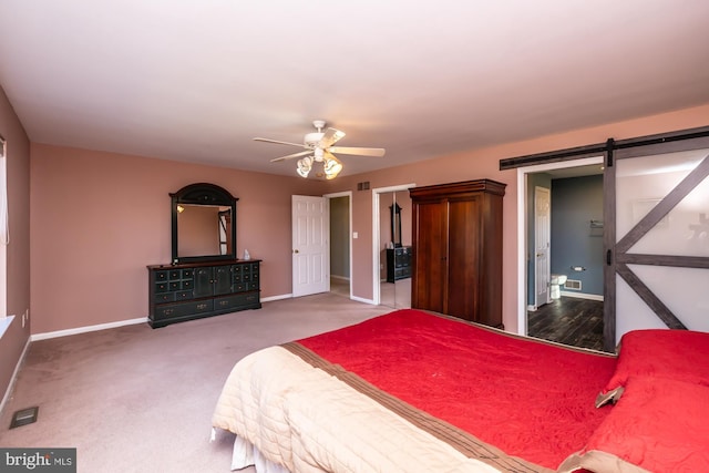 bedroom with a barn door, ceiling fan, and carpet