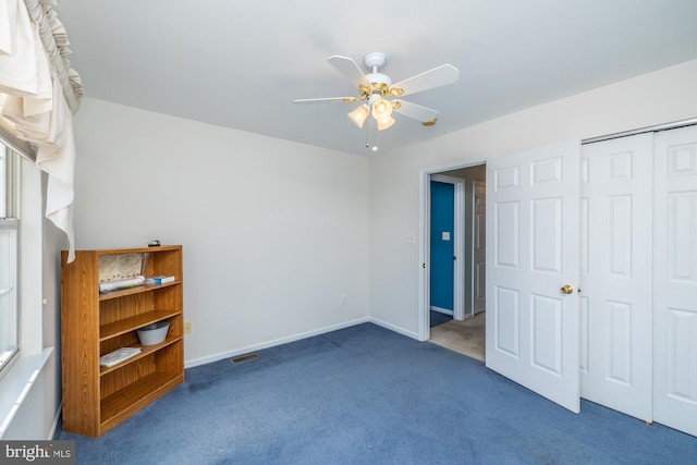 unfurnished bedroom with ceiling fan, a closet, and dark carpet