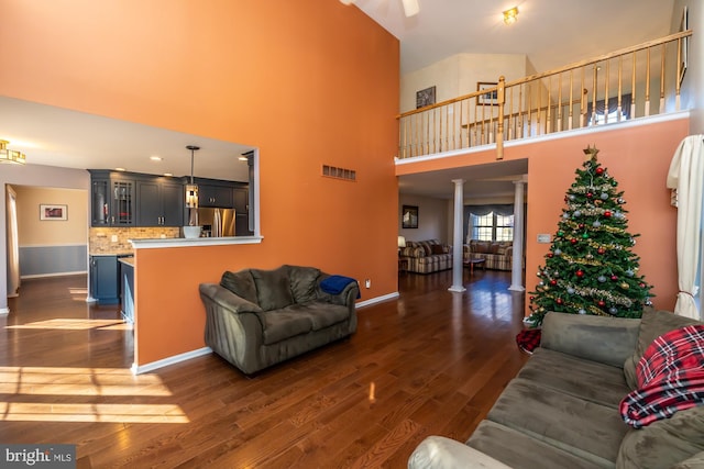 living room featuring a towering ceiling, dark hardwood / wood-style floors, and ornate columns