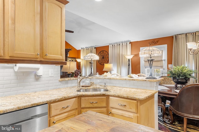 kitchen with light brown cabinetry, sink, stainless steel dishwasher, and lofted ceiling