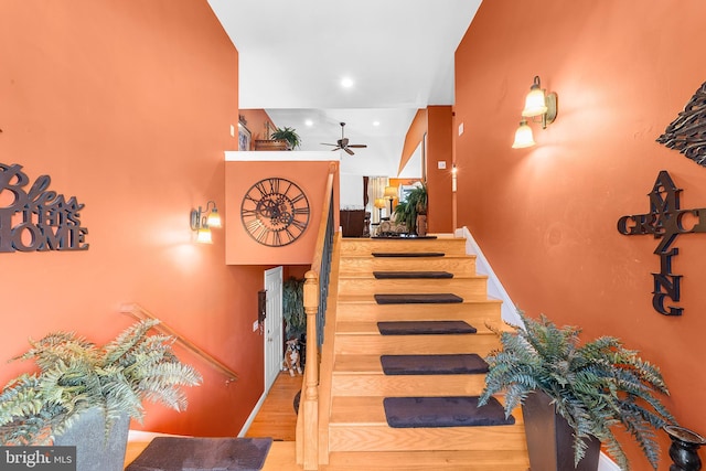 stairs featuring ceiling fan and hardwood / wood-style flooring