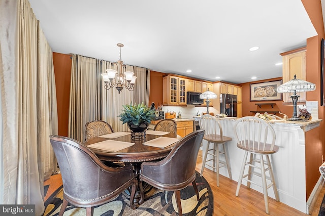 dining area with light hardwood / wood-style floors and an inviting chandelier