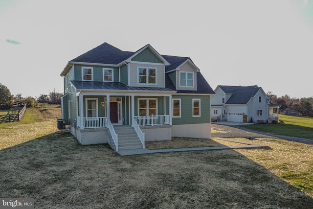 view of front of home with central air condition unit, a front lawn, a porch, and a garage