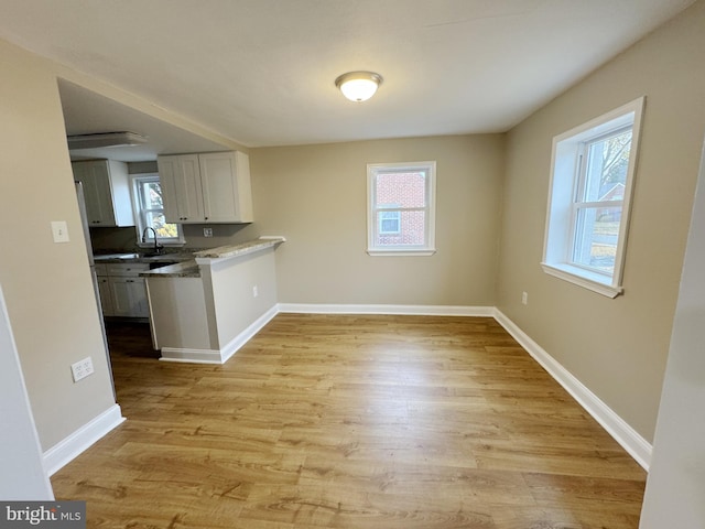 kitchen with light hardwood / wood-style floors, white cabinetry, a wealth of natural light, and sink