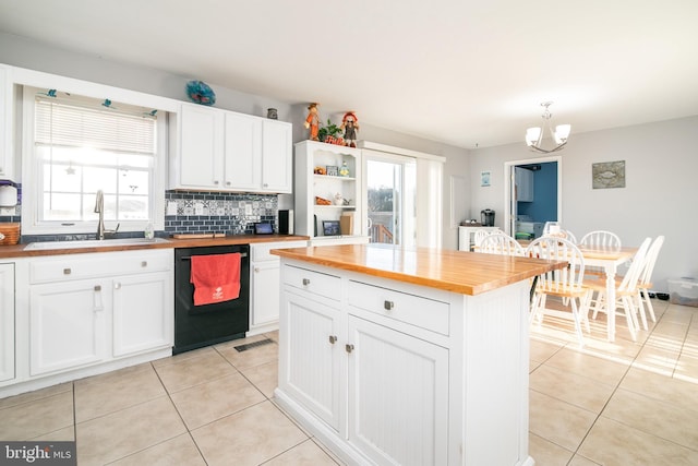 kitchen featuring wood counters, dishwasher, white cabinetry, and decorative light fixtures